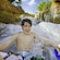 A boy smiles widely as he holds the handle of an inner tube on a water ride
